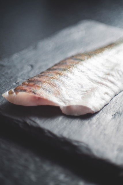 Raw white fish fillet with the skin on, resting on a slate board